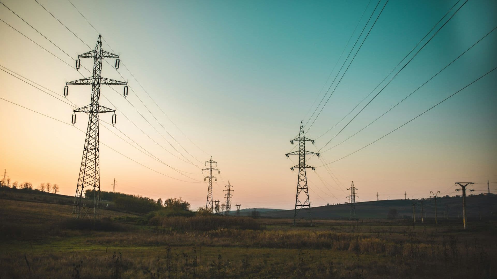 Ingénieur au casque devant une ligne électrique et des panneaux solaires